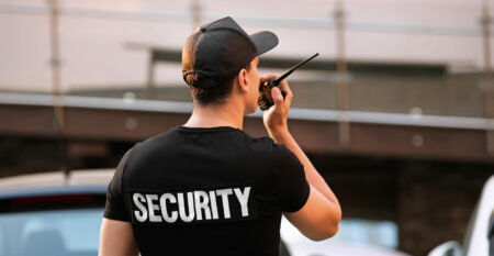 Male security guard with portable radio, outdoors